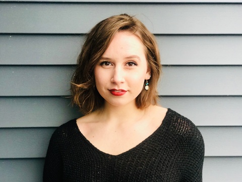 A photo of a woman with short, brown hair and a black shirt. She is smiling at the camera.